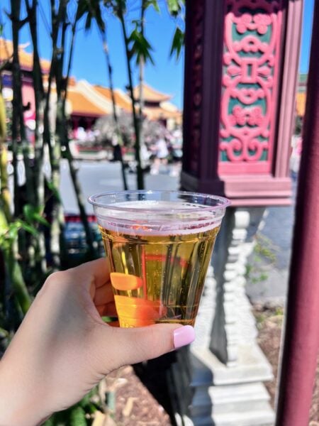 Hand holds beer in China pavilion at Epcot, valid ID needed for purchase.