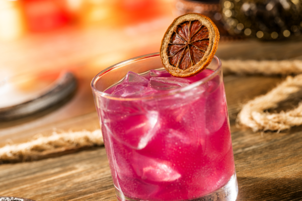 Pink cocktail with ice and dried orange slice, alcohol at Magic Kingdom