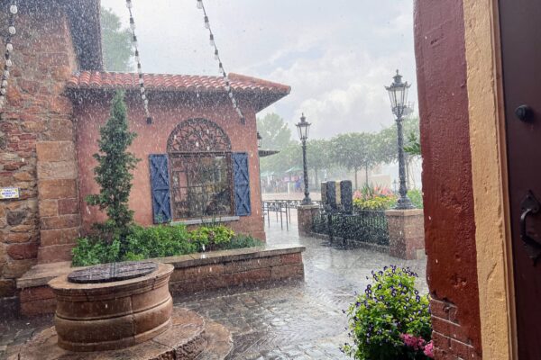 Rain falling on a charming Italian-themed courtyard with a well and lanterns.