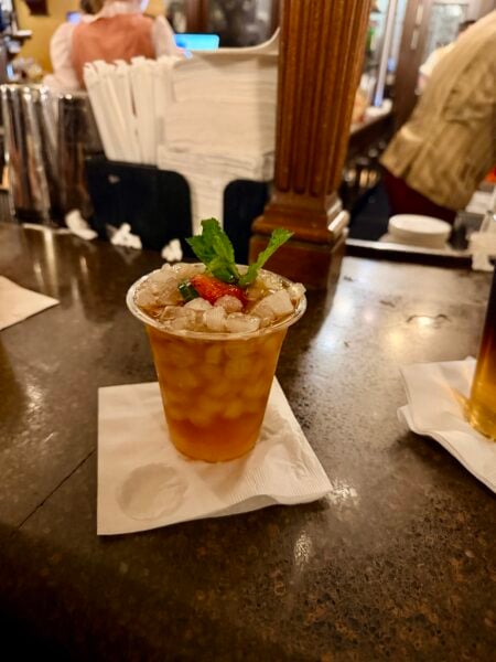 Pimm's Cup in a plastic cup with crushed ice, strawberry, cucumber, and mint on the bar at Rose & Crown Pub in EPCOT