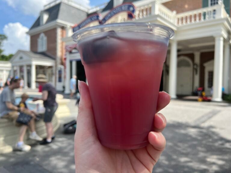 Moonshine Sour from the Regal Eagle Outdoor Bar held up in front of the American Adventure at EPCOT